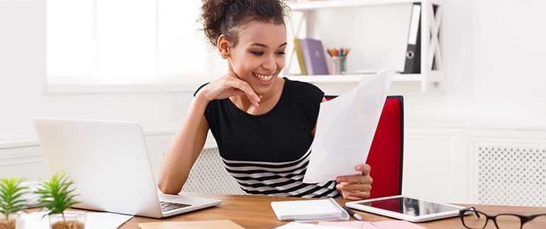 Woman working at a desk with a laptop.