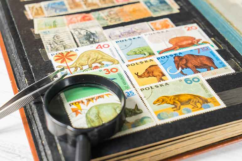 stamp collection book with tweezers and magnifying glass sitting on top