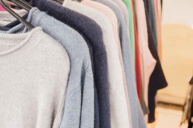 colorful cashmere sweaters in a closet