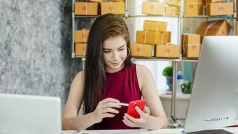 Woman sitting at her desk on her phone.