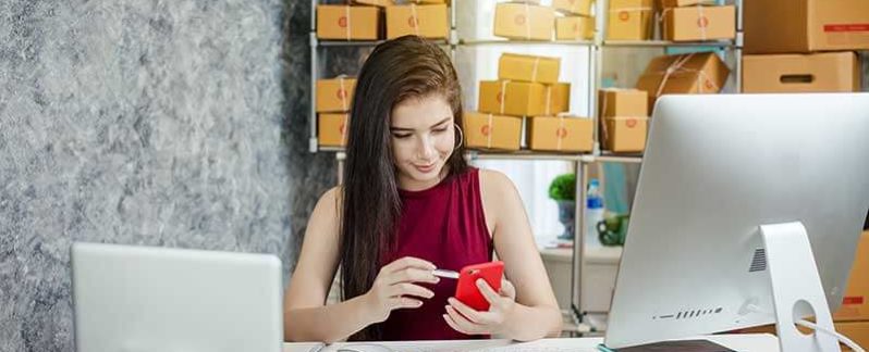 Woman sitting at her desk on her phone.