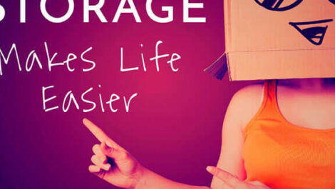 A woman with a box inscribed with a face on it, with the words "Storage Makes Life Easier" on the wall