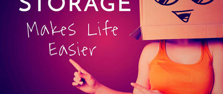 A woman with a box inscribed with a face on it, with the words "Storage Makes Life Easier" on the wall