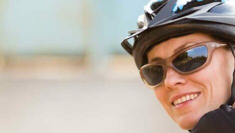 Person facing backwards, smiling, wearing sunglasses and a bike helmet.