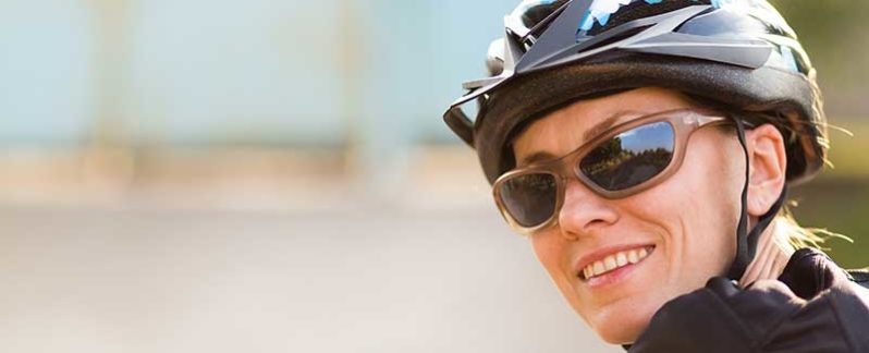 Person facing backwards, smiling, wearing sunglasses and a bike helmet.