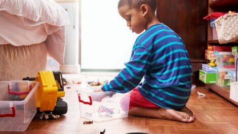 A child putting toys into a box.