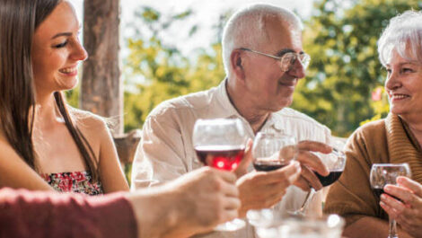 Two couples holding glasses full of wine.