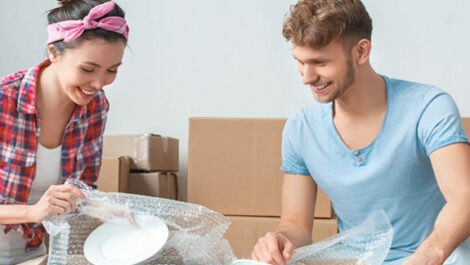 Man and woman wrapping item in bubble wrap.