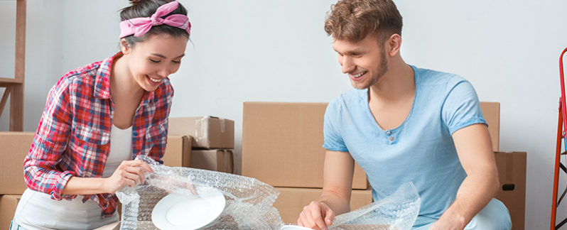 Man and woman wrapping item in bubble wrap.