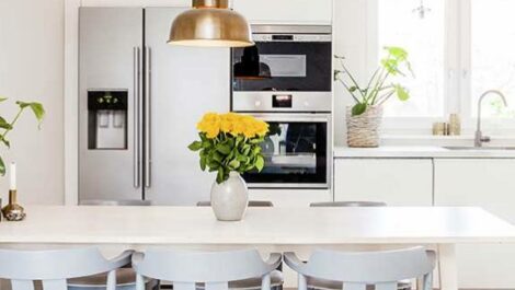 A pristine kitchen, with yellow flowers in a vase on the counter