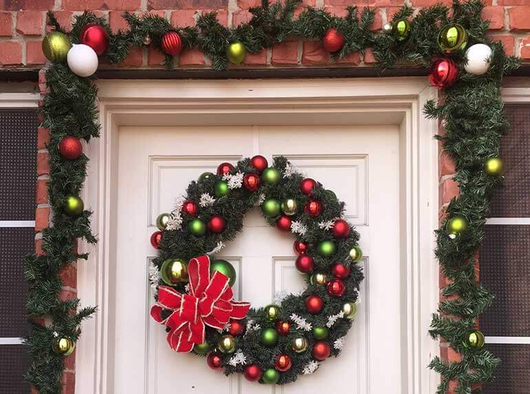 Christmas garland draping front door with wreath