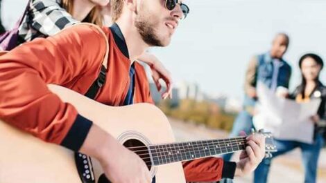 Man playing his guitar outside.