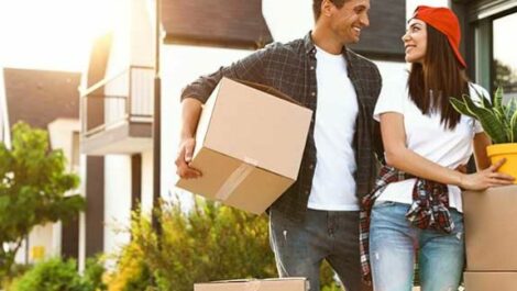 Man and woman holding moving boxes and plants.