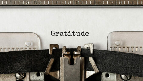 A typewriter remains motionless after typing the word "gratitude" on a piece of paper