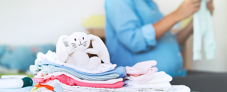 Stuffed animal sitting on folded clothes.