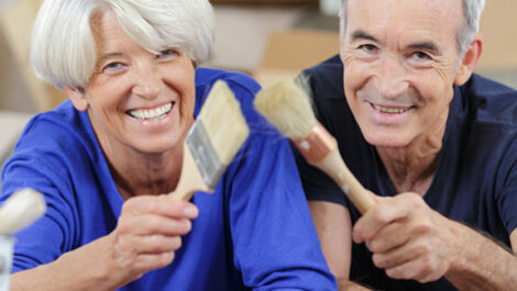 Two seniors holding paint brushes, ready to remodel their home