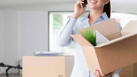 A woman talks on the phone while holding a box of her belongings.