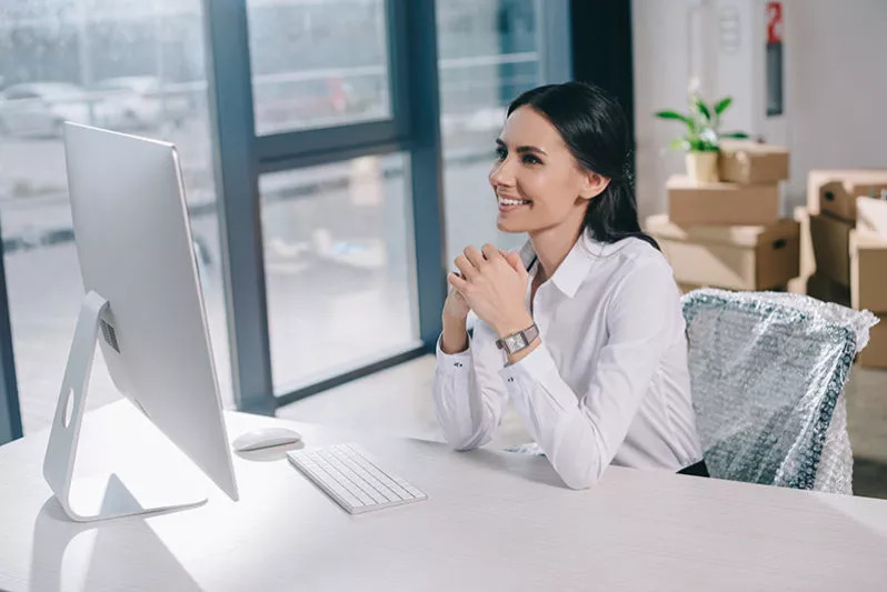 Woman looking at desktop comupter, smiling.