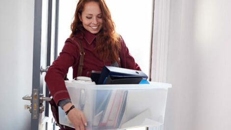 Woman holding a box full of office folders.