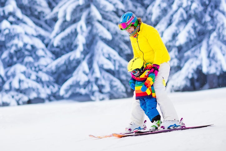 Mother helping young child learn how to ski.