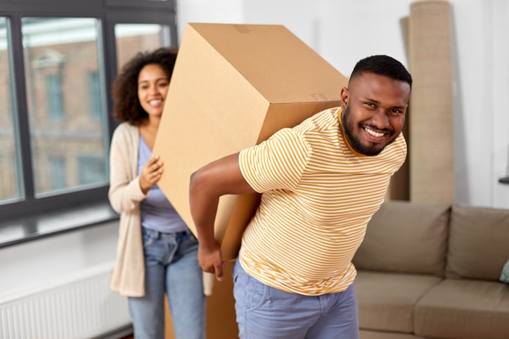 Black couple carrying a large moving box together