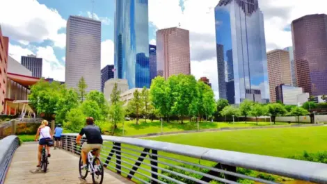 A man and a woman riding their bikes across a bridge in Houston, TX