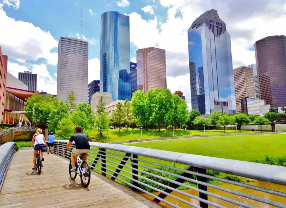 A man and a woman riding their bikes across a bridge in Houston, TX