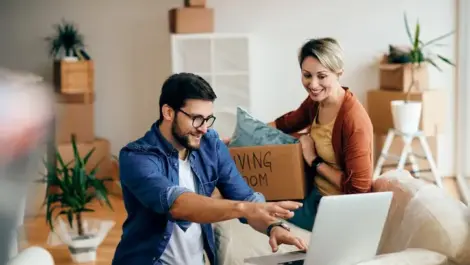 Happy man and his wife using laptop while moving into their new home.