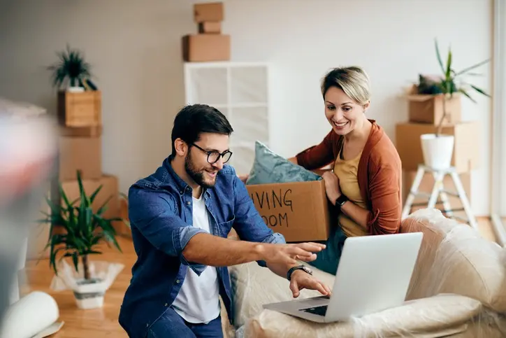 Happy man and his wife using laptop while moving into their new home.