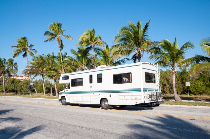 An RV on the road in Key West, with palm trees in the background