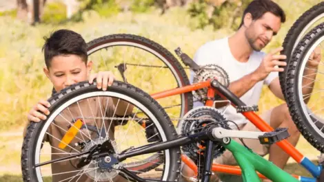 A father and son inspecting their bikes together