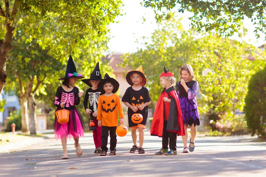 A group of children in Halloween costumes walking together down a road