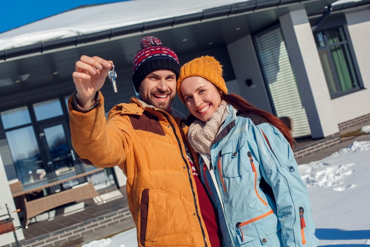 Happy couple in winter gear holing up a key.