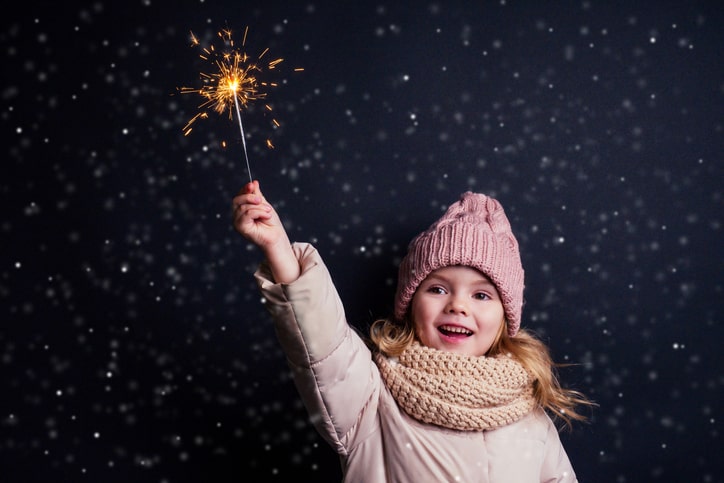 A young girl celebrating the new year with a sparkler in hand.