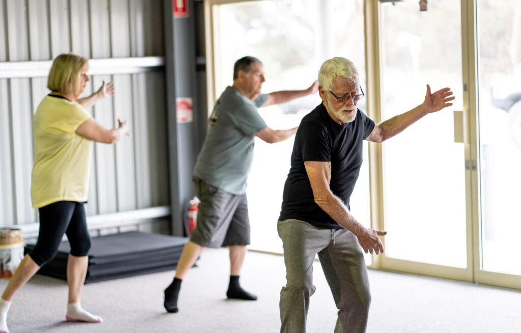 Senior citizens doing aerobic exercises at gym.
