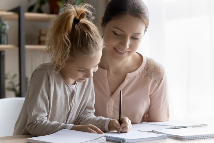 Mother and daughter write down their goals together at a desk.
