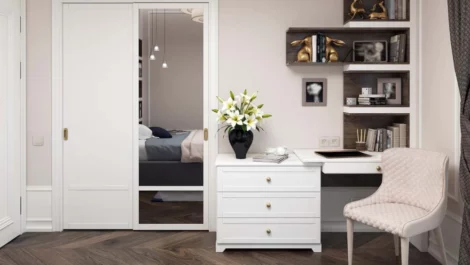 Interior of a bedroom with a mirror, chair and bookcase.