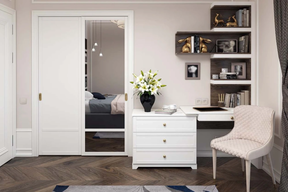 Interior of a bedroom with a mirror, chair and bookcase.