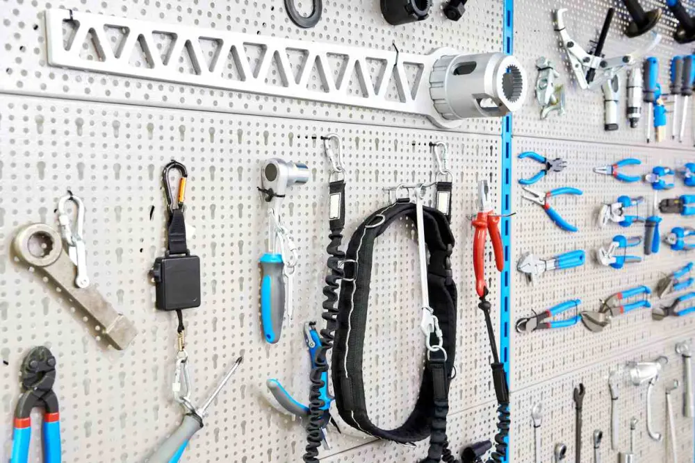 An assortment of tools, such as pliers and wrenches, stored on a pegboard in a garage