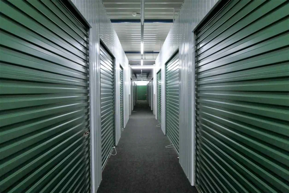 Storage units with green doors in a dimly-lit hallway