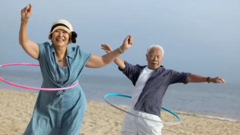 Mature couple hula-hooping on the beach.