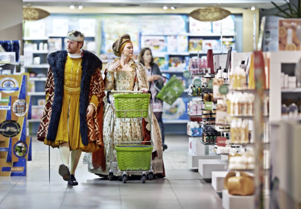 Two people dressed in medieval attire shopping in a modern store.