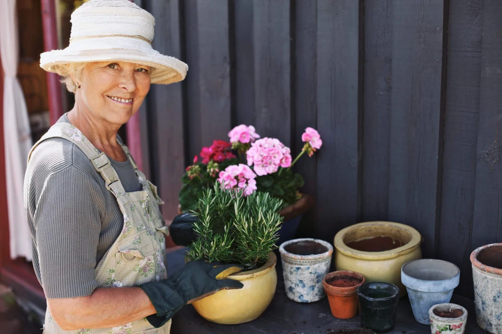 Mature woman smiling while repotting a plant.