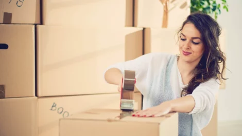 Woman sealing a box using a tape gun.