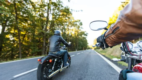 Two men driving motorcycles down the highway.