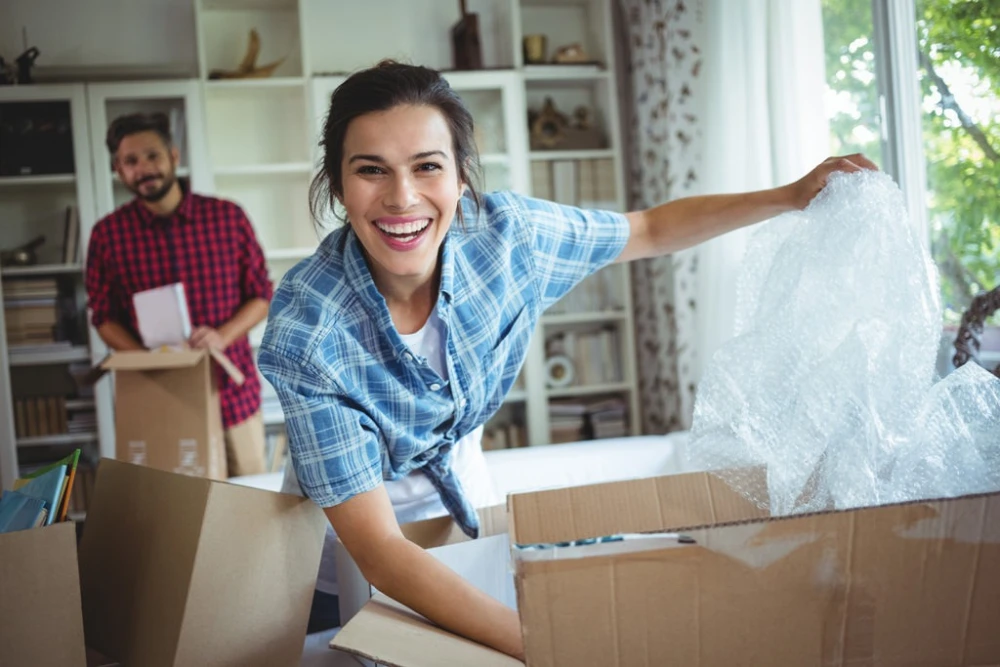 smiling woman packing moving boxes in living room