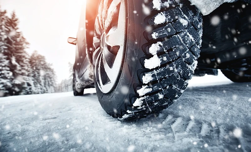 close-up of snow tires on a car driving during a winter move to a new home