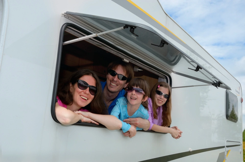 Family smiling while looking out window of rv