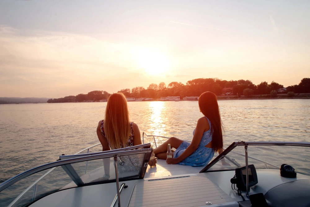 Women sitting on a boat having a drink as the sun sets.