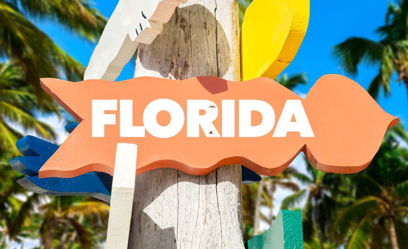 Orange Florida sign hanging on a wooden post.